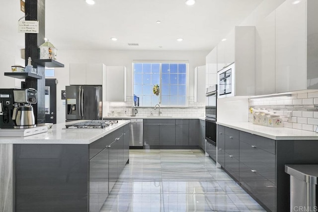 kitchen with decorative backsplash, sink, white cabinetry, and stainless steel appliances