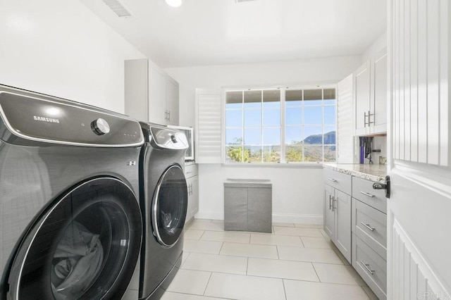 washroom with light tile patterned flooring, washer and dryer, and cabinets