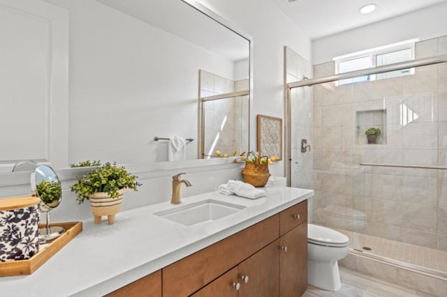 bathroom with toilet, a shower with shower door, and vanity