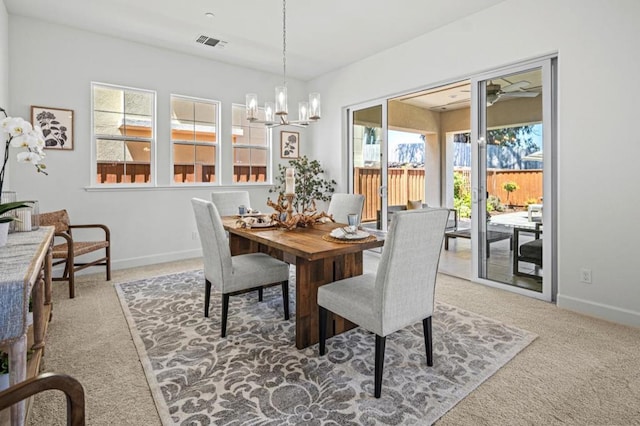 carpeted dining area with an inviting chandelier