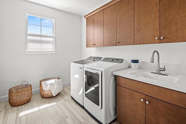 clothes washing area featuring sink, washing machine and clothes dryer, and cabinets