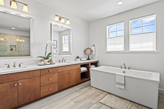 bathroom with wood-type flooring, vanity, and shower with separate bathtub