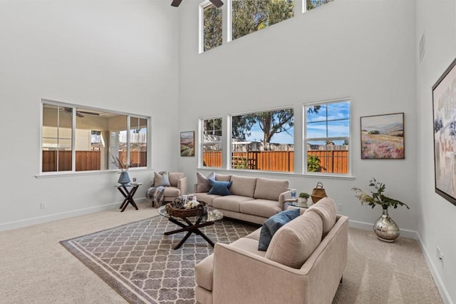 carpeted living room featuring ceiling fan and a towering ceiling