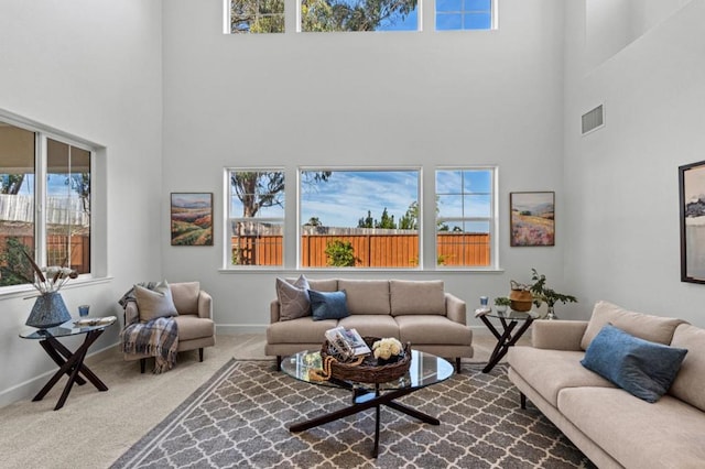 living room featuring carpet flooring, a towering ceiling, and plenty of natural light