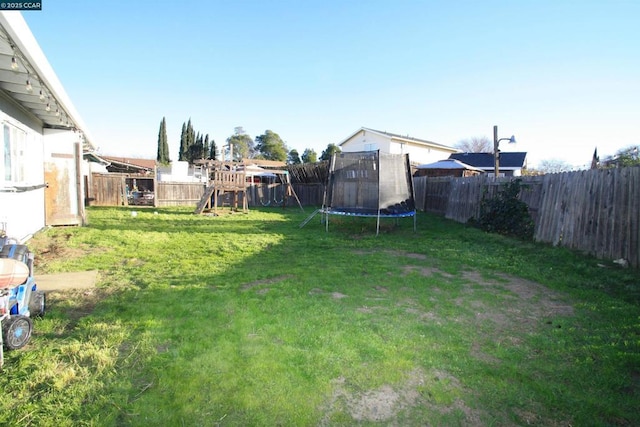 view of yard with a playground and a trampoline