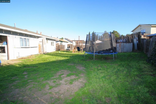 view of yard with a playground, a trampoline, and washer / clothes dryer