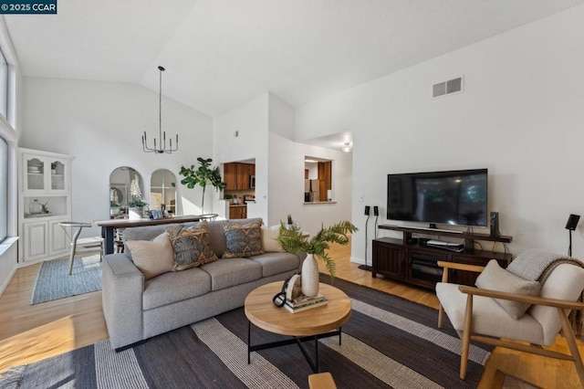 living room featuring lofted ceiling, a chandelier, and light wood-type flooring