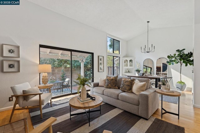 living room featuring light wood-type flooring, a chandelier, and vaulted ceiling