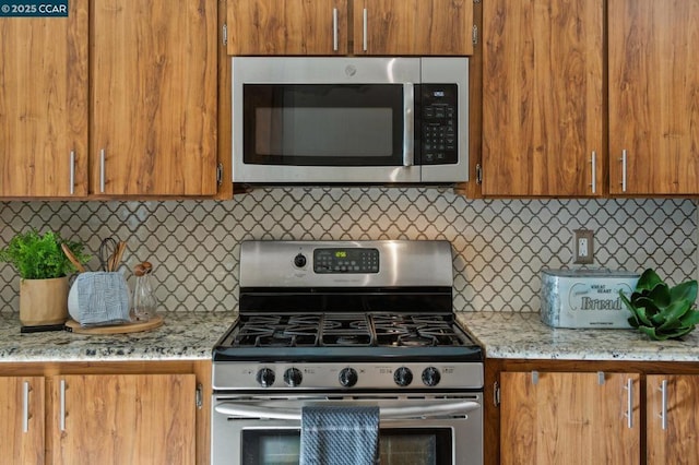 kitchen with stainless steel appliances, tasteful backsplash, and light stone counters