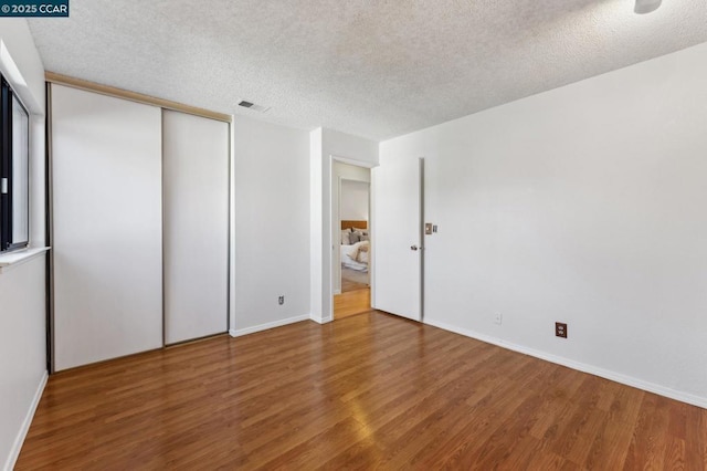 unfurnished bedroom featuring a closet, a textured ceiling, and hardwood / wood-style flooring