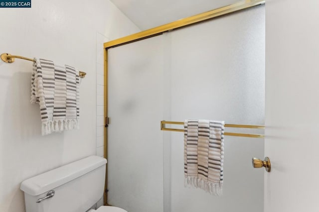 bathroom featuring a shower with shower door and toilet