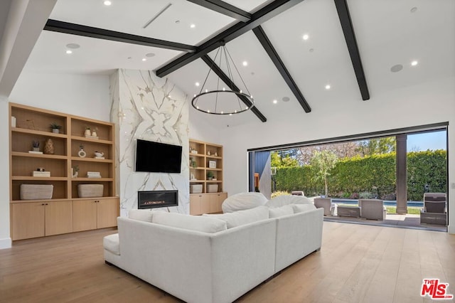 living room featuring a healthy amount of sunlight, a premium fireplace, high vaulted ceiling, beam ceiling, and light hardwood / wood-style flooring