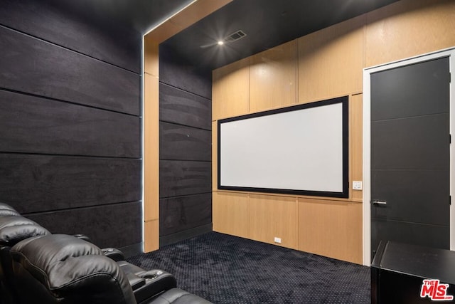 home theater room featuring carpet flooring and wooden walls