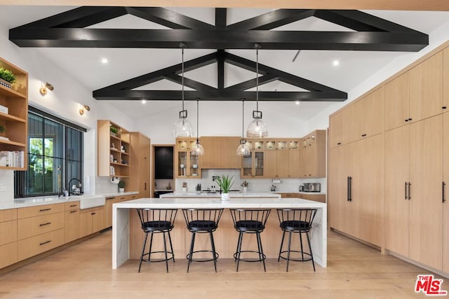 kitchen with light brown cabinets, backsplash, a spacious island, and sink