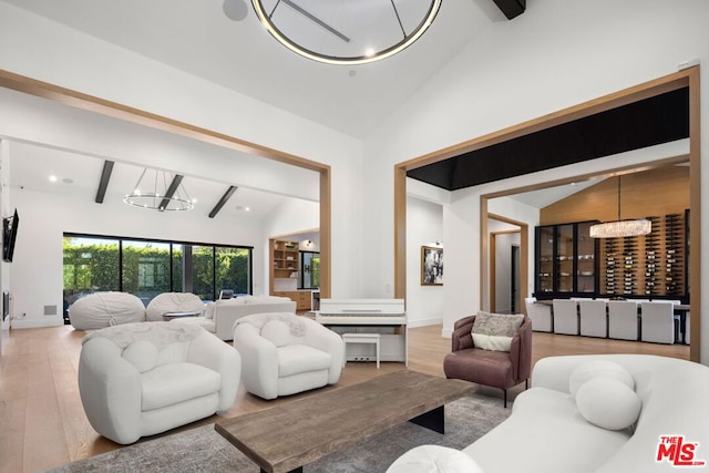 living room featuring high vaulted ceiling, light hardwood / wood-style flooring, beamed ceiling, and an inviting chandelier