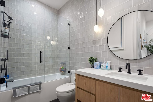 full bathroom with toilet, bath / shower combo with glass door, tile walls, backsplash, and vanity