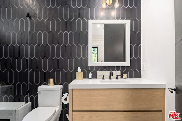 bathroom with toilet, vanity, and a shower