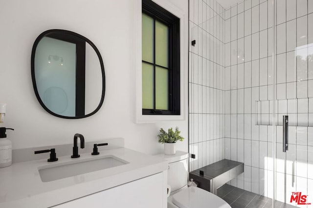 bathroom featuring a shower with shower door, vanity, and toilet