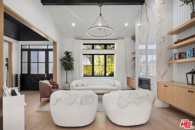 living room featuring a high end fireplace, lofted ceiling, and light hardwood / wood-style flooring