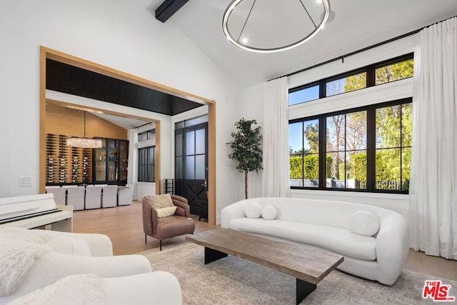 living room featuring high vaulted ceiling, a chandelier, beamed ceiling, and light wood-type flooring