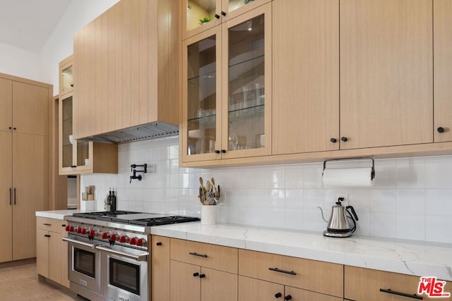 kitchen featuring light stone countertops, double oven range, backsplash, and light brown cabinets