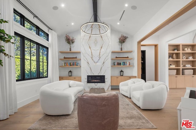 living room with a high end fireplace, light hardwood / wood-style floors, and high vaulted ceiling