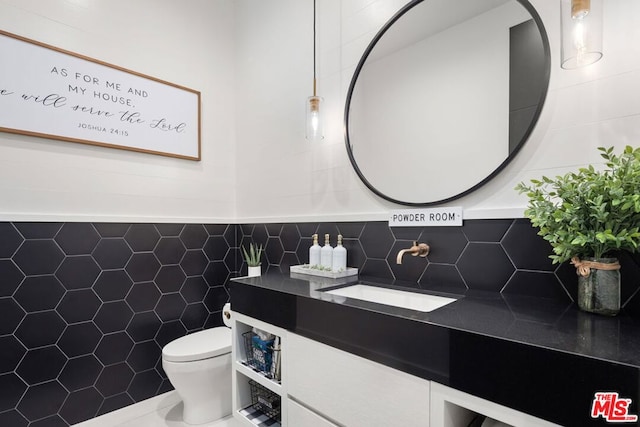 bathroom featuring toilet, vanity, tile walls, and tile patterned floors