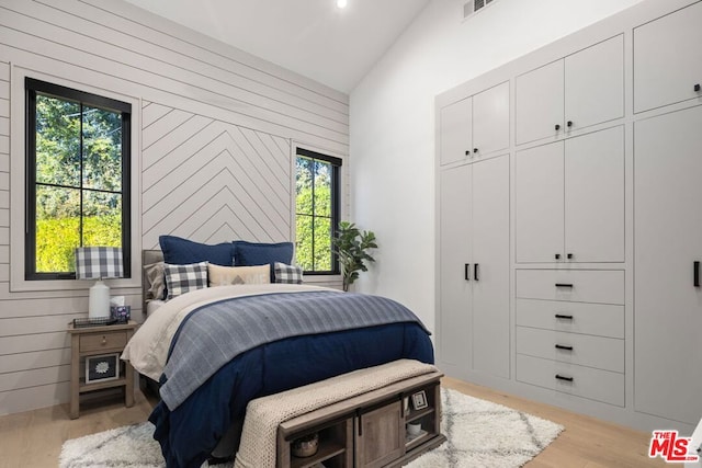 bedroom with multiple windows, wood walls, and vaulted ceiling