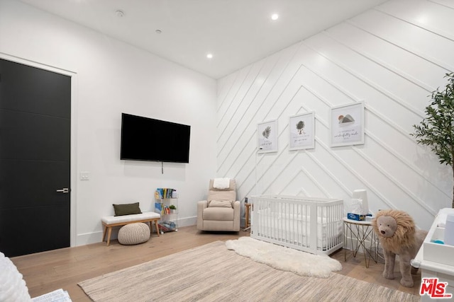 bedroom featuring hardwood / wood-style flooring and a crib