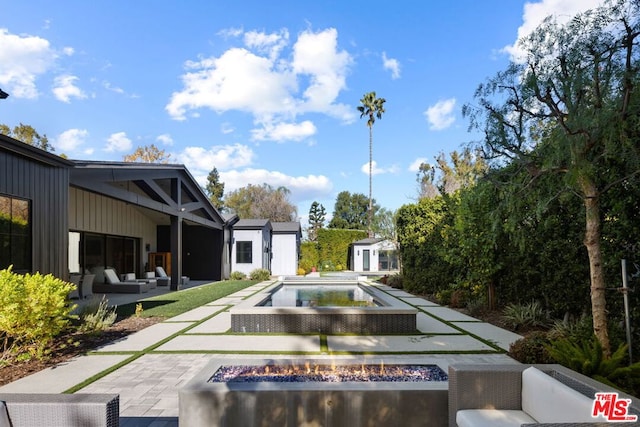 view of pool featuring an outdoor living space with a fire pit, a patio area, and an outdoor structure