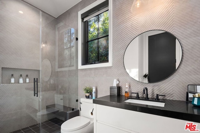 bathroom featuring toilet, tile walls, a shower with door, and vanity