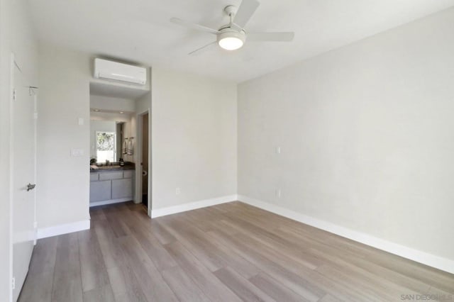 unfurnished room with ceiling fan, a wall mounted AC, and light hardwood / wood-style floors