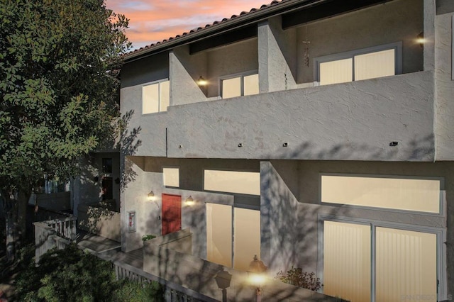 back house at dusk featuring a balcony