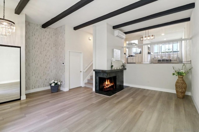 living room featuring light wood-type flooring, a chandelier, an AC wall unit, and beamed ceiling