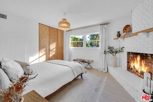 bedroom featuring a brick fireplace and wood walls