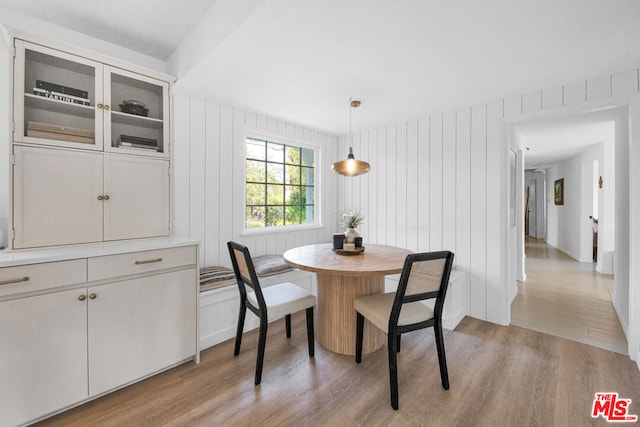 dining space with light hardwood / wood-style floors, breakfast area, and wooden walls