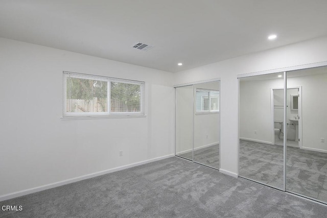 unfurnished bedroom featuring carpet floors and multiple closets