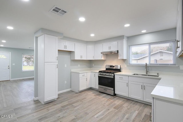 kitchen with light hardwood / wood-style flooring, sink, gas stove, and white cabinetry