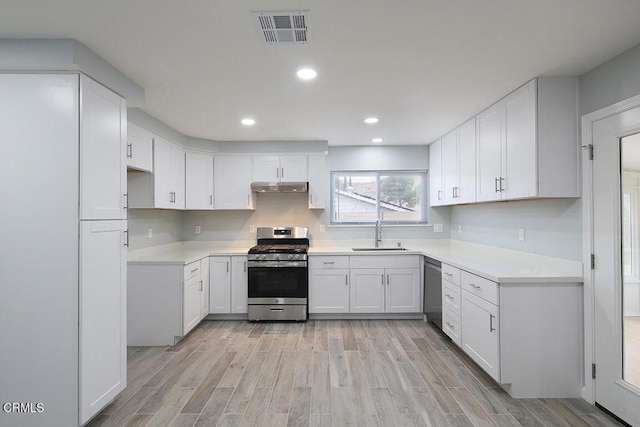 kitchen featuring light wood-type flooring, appliances with stainless steel finishes, sink, and white cabinetry