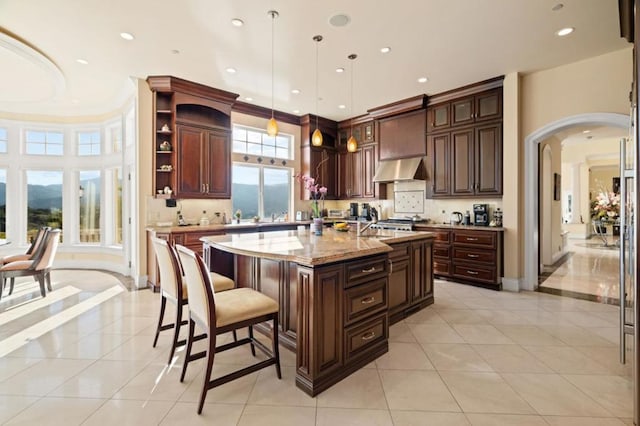 kitchen featuring decorative light fixtures, a kitchen island with sink, light stone countertops, and light tile patterned flooring