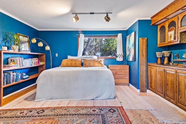 bedroom featuring crown molding, track lighting, a textured ceiling, and light wood-type flooring