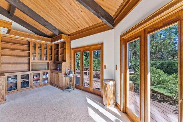 interior space featuring wood ceiling, light colored carpet, a healthy amount of sunlight, and lofted ceiling with beams