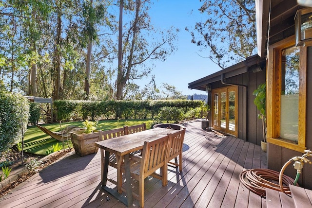 wooden terrace featuring french doors and a lawn