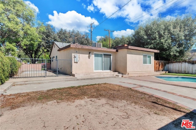 rear view of house with a fenced in pool and a patio area