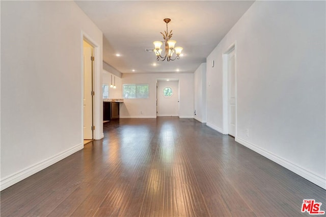 unfurnished living room featuring dark wood-type flooring and a chandelier