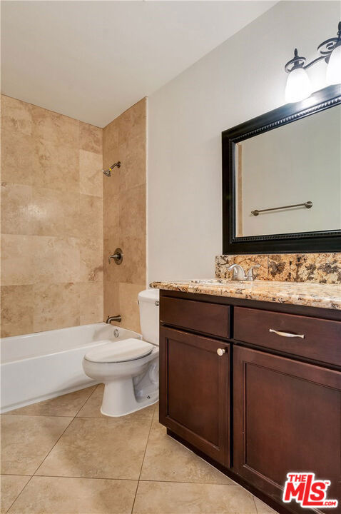 full bathroom with toilet, tiled shower / bath, tile patterned flooring, and vanity