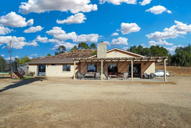 back of property featuring a trampoline, a pergola, and a patio