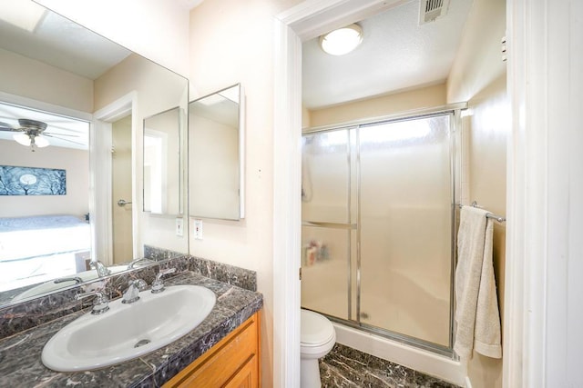 bathroom featuring toilet, ceiling fan, walk in shower, and vanity