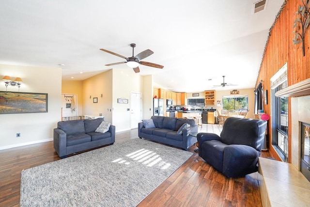 living room featuring dark wood-type flooring, wood walls, and ceiling fan