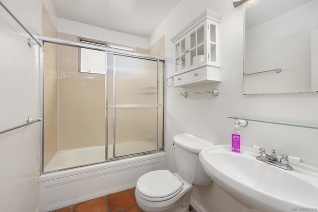 full bathroom featuring sink, bath / shower combo with glass door, toilet, and tile patterned flooring